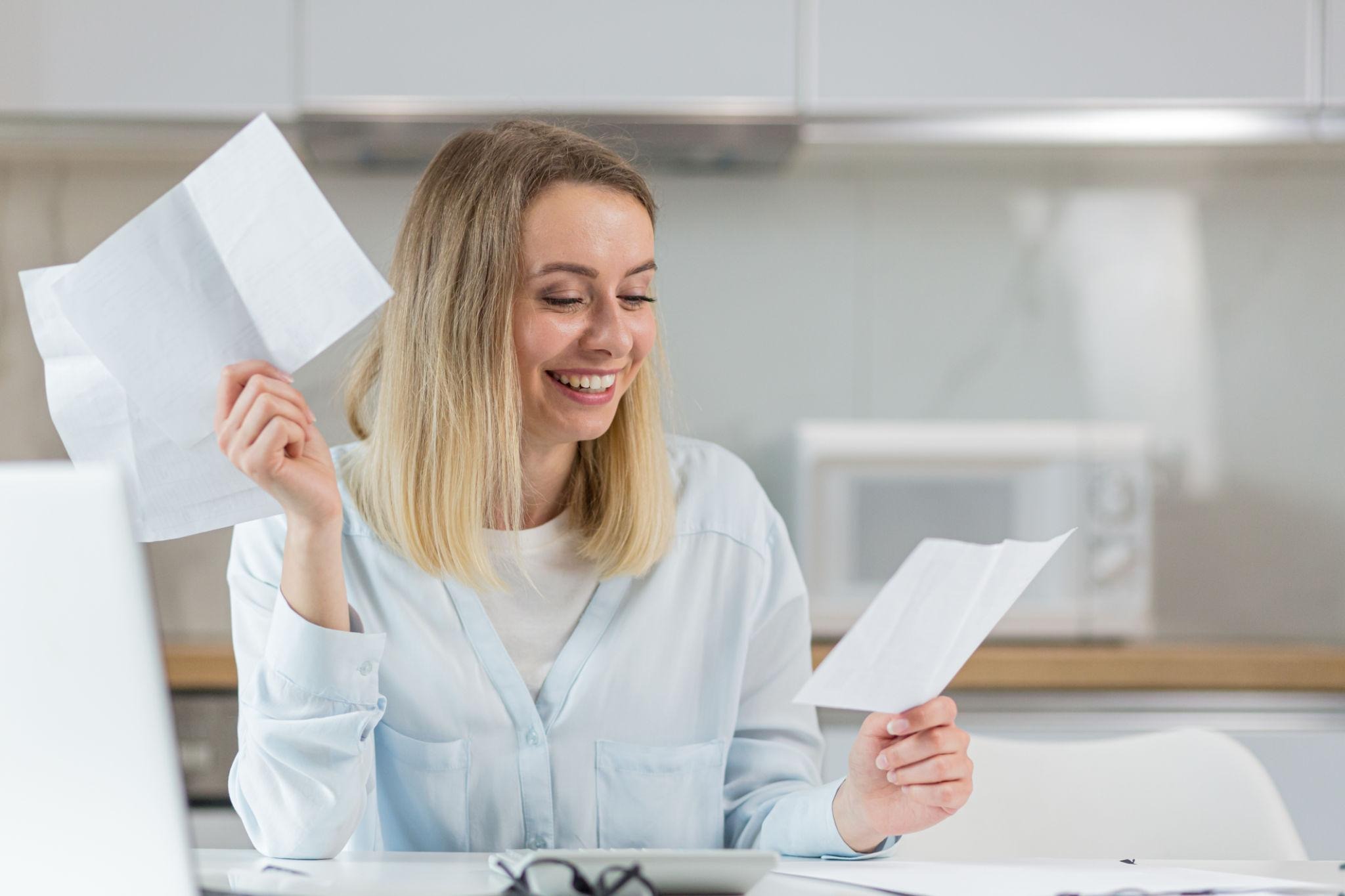 Woman smiling while reviewing loan paperwork at home after finding a lower rate